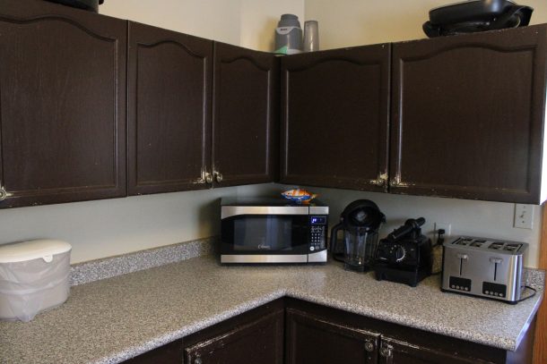 A view of a microwave on a kitchen counter in a kitchen with brown cupboards.