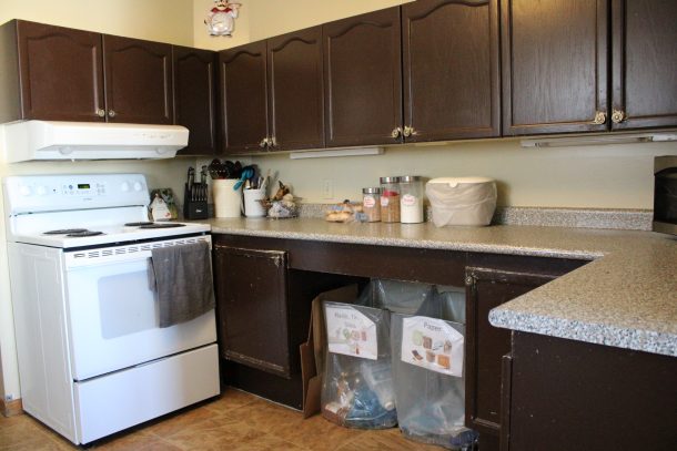 A view of a stove in a kitchen with brown cupboards.